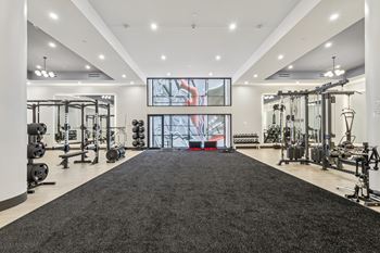 A spacious gym with a variety of equipment and a large mirror on the wall at LiveWell Apartments, Pittsburgh, PA, 15222